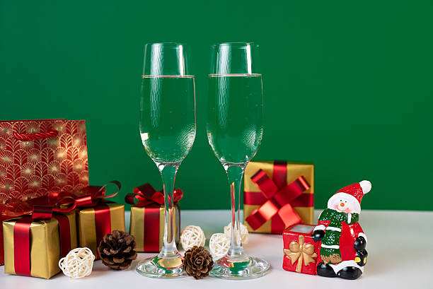 istock Holiday champagne flutes with gift boxes on green background 2235782863