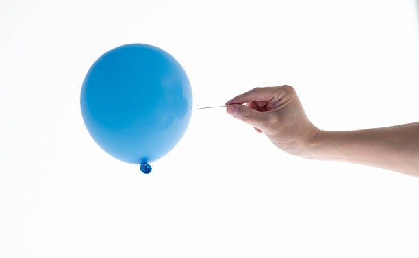 istock Man hand holding a needle close to blue balloon on white background 2235784598
