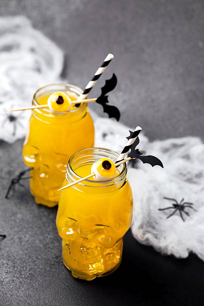 istock Spooky yellow drinks in skull jars with candy eyes and bat decor 2235784795