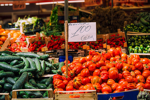 A colorful display of fresh fruits and vegetables at a market in Sicily, Italy. Seasonal produce is organized in wooden crates under natural lighting, creating an inviting and lively atmosphere.