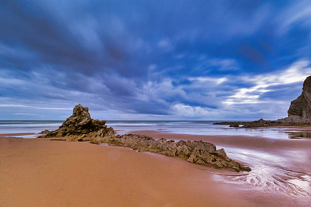 istock Cloudy sunset over a rugged Atlantic beach - A long-exposure shot of a dramatic, cloudy sunset over a rugged, rocky beach on the Atlantic coast. 2235791391