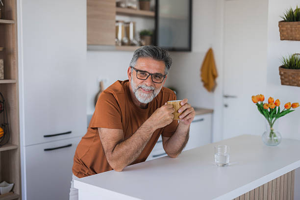 istock Smiling senior man enjoying a cup of coffee in his modern kitchen 2235793983