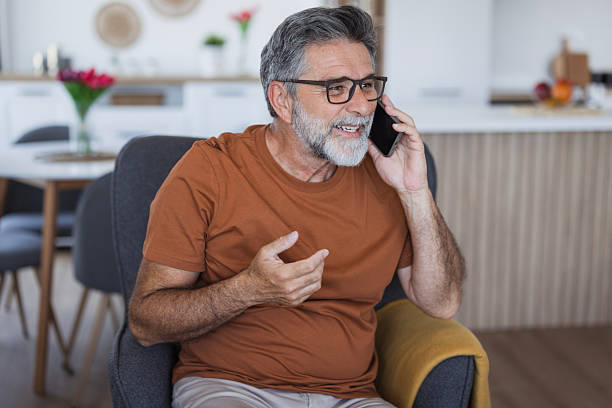 istock Senior man talking on mobile phone at home and smiling 2235794074