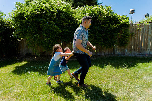 istock Latino Father and daughters Playing Together in backyard on a sunny day 2235795131