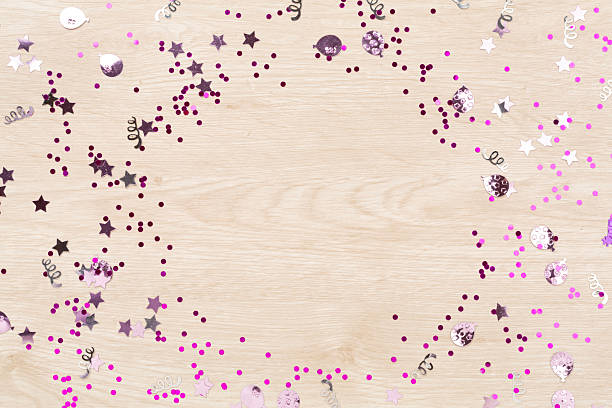 Party pink confetti on wooden background, top view