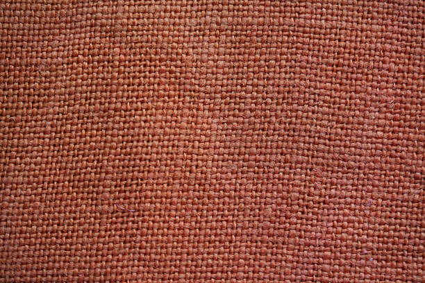 top view of orange burlap fabric showing coarse woven fibers. Detailed textile surface suitable for material backgrounds and design references.