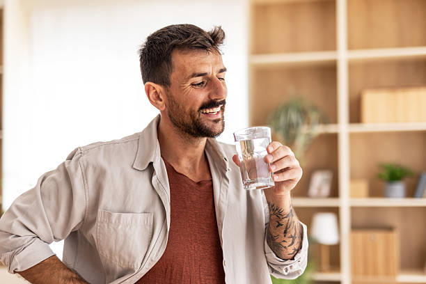 istock Smiling man drinking fresh water glass at home 2235798656