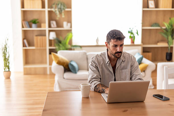 istock Focused young man working from home on laptop at wooden table 2235798797