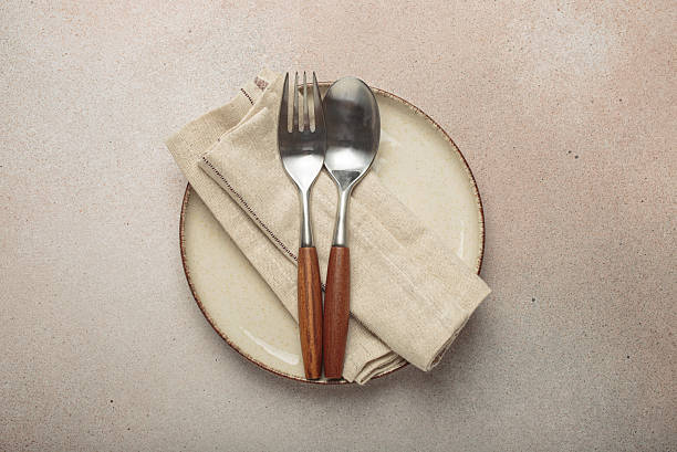 istock Elegant table setting featuring plate, napkin, fork, and spoon on neutral background top view 2235799984