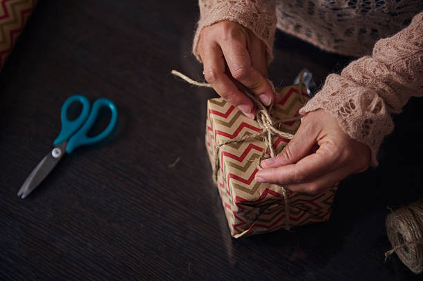 Hands Wrapping a Gift with Decorative Paper and Twine