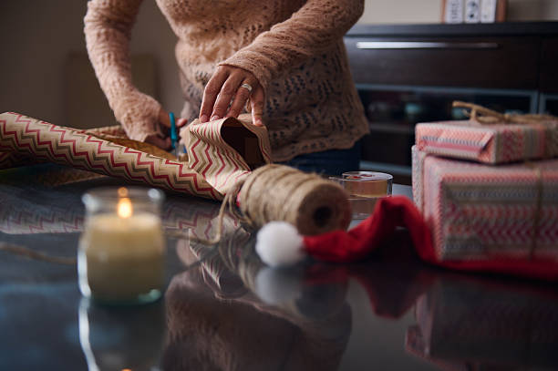 istock Person Wrapping Gifts with Candles and Decorations on a Table 2235806623