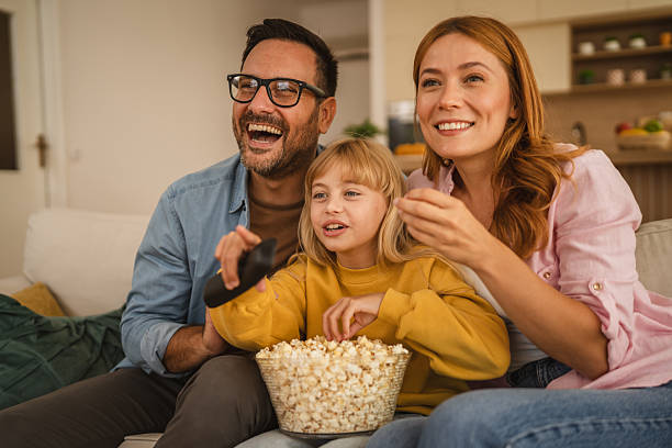 istock Happy family watching television and eating popcorn on sofa 2235813957