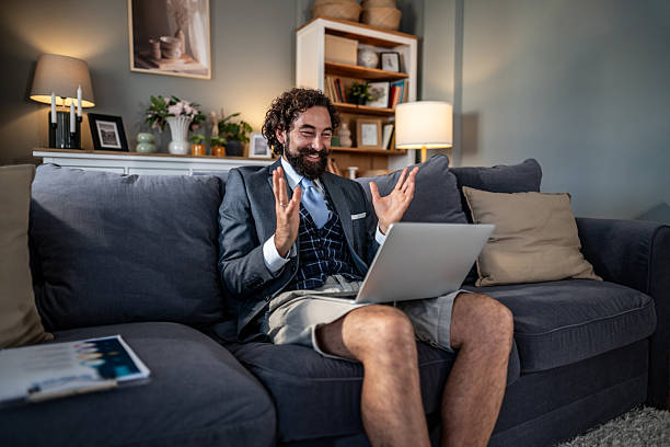 istock Businessman making video call wearing suit jacket and shorts on sofa 2235815549