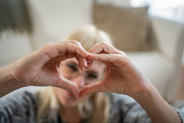 istock Woman making heart shape with hands at home 2235816950