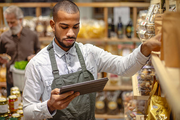 istock Focused Multiracial Male Grocery Worker Checking Inventory with Tablet in a Busy Store 2235826849