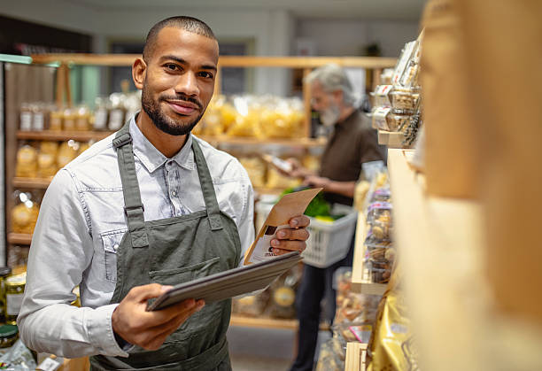 istock Professional Mixed-Race Grocery Store Worker In Gray Apron Checking Inventory With Digital Tablet 2235826855