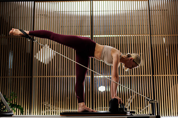 istock Engaging yoga session featuring a person practicing Pilates on a reformer in a modern, well-lit studio during evening hours 2235827045