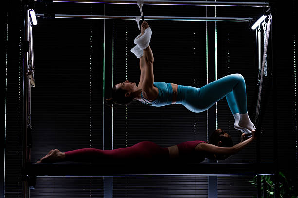 istock Two women practicing advanced aerial yoga poses in a dimly lit studio with large windows, showcasing strength and flexibility during an evening session 2235827147