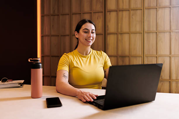 istock Young woman working on a laptop at a modern workspace during daytime with a water bottle beside her 2235827198