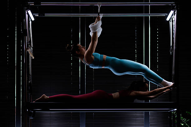 istock Pilates practice in a studio with two women performing strength exercises on a reformer machine during an indoor session in low light 2235827541