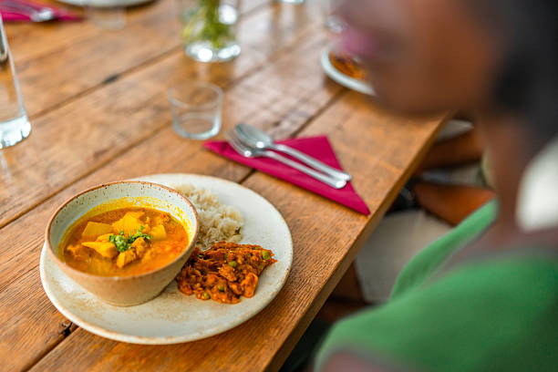A person admires a plate of Indian cuisine featuring aromatic curry and rice after mastering skills in a cooking class, reflecting diverse culinary achievements.
