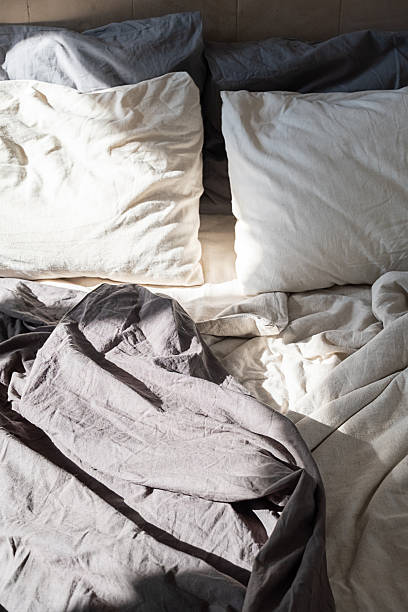 istock Unmade bed with crumpled linen sheets in morning light. 2235829604