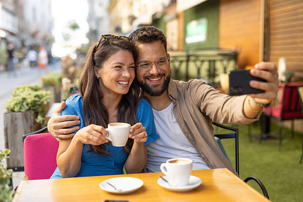 istock Smiling couple taking selfie during cafe outing with coffee cups. 2235829614