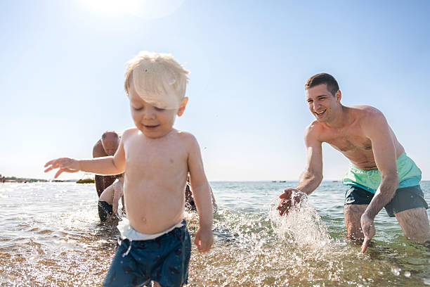 istock Multi-generation family playing in shallow water at seaside 2235831029