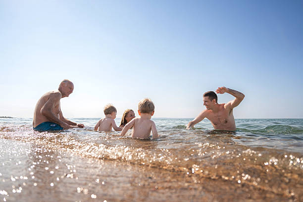 istock Multi-generation family playing in shallow water at seaside 2235831030