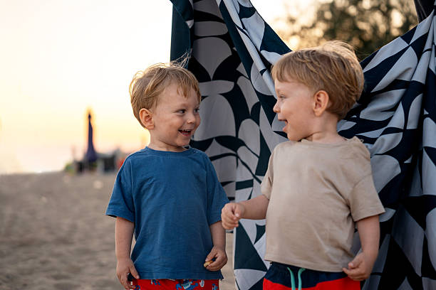 Twin brother having fun time together on sandy beach during sunset
