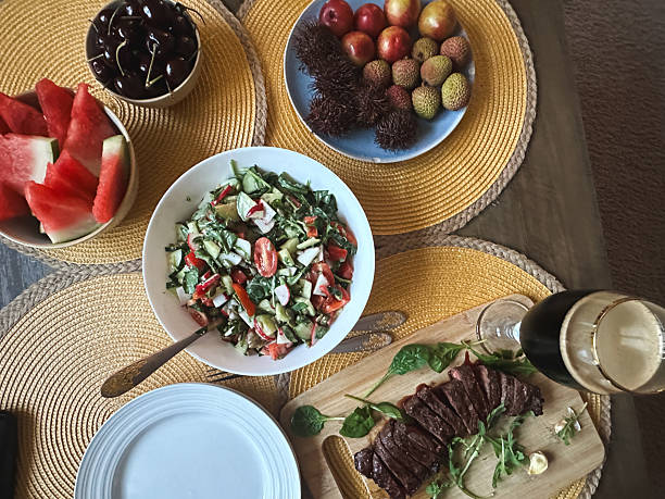 Sliced steak, salad, and fresh fruits arranging on dining table