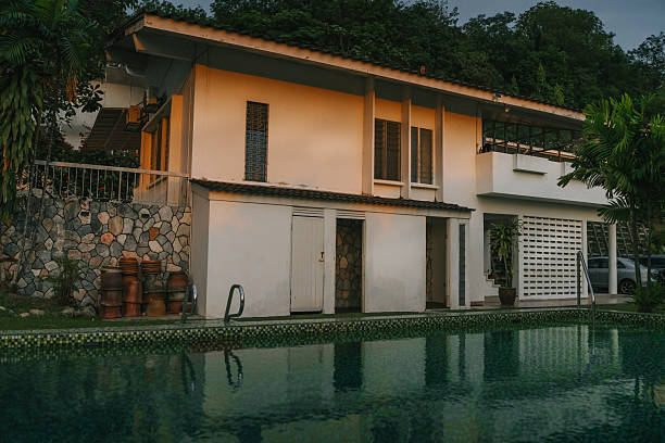 Evening view of a tropical-style house with swimming pool, stone walls, and greenery, photographed at golden hour. Located in Petaling Jaya, Malaysia