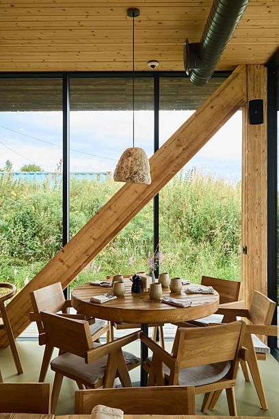 istock Cozy wooden dining area with large windows and greenery outside 2235837988