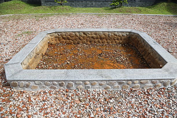 A small stone wall with a dirt floor. The dirt is brown and has some rocks in it