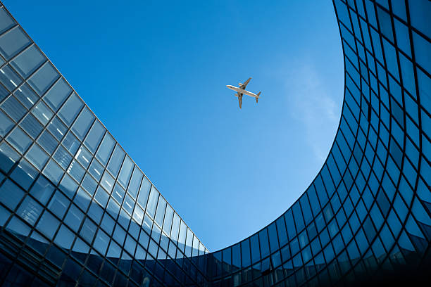 This modern architectural marvel depicts an airplane soaring through a clear sky, capturing the essence of urban connectivity and technological advancement. The visual composition highlights the contrast between the smooth glass facade and the dynamic flight of the aircraft, evoking a sense of progress and innovation.\n﻿