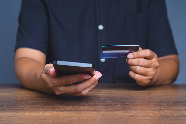 istock Close-up of hands using a smartphone and a credit card, representing digital transaction and e-commerce. 2235842160