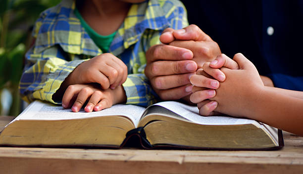 istock The boy prayed on the table. The family prayed together. 2235843897