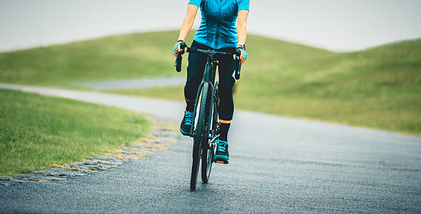 Winsome Cute Caucasian Female Cyclist With Road Bike Posing Outdoors While Prepared for the Race Against Autumn Background.Horizontal Image Composition