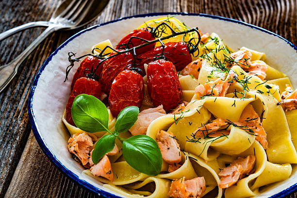 istock Pasta with baked salmon and cherry tomato on wooden table 2235855430