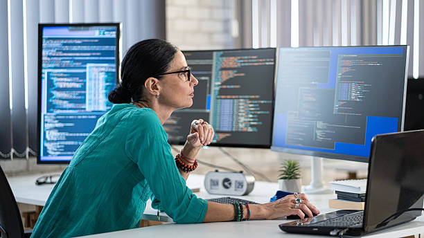 Female freelance developer coding and programming. Coding on two with screens with code language and application. stock photo