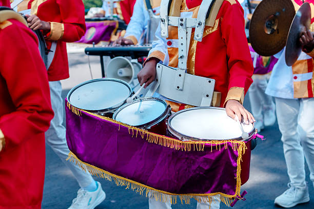 istock Close-up of a marching band drummer in a red and gold uniform playing multiple drums during a parade, showing rhythm, teamwork, culture, and festive celebration. 2235856450