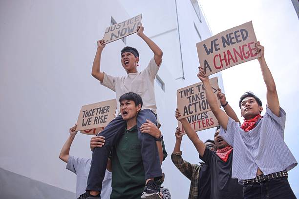 Amidst Group Of Demonstrators With Various Protest Signs And One Activist Elevated While Energetically Leading Chant