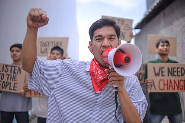 istock Determined Protestor With Megaphone And Raised Fist Demands Change During Demonstration 2235859195