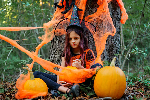 istock Child dressed in witch costume with pumpkins in a forest during Halloween celebration 2235859262