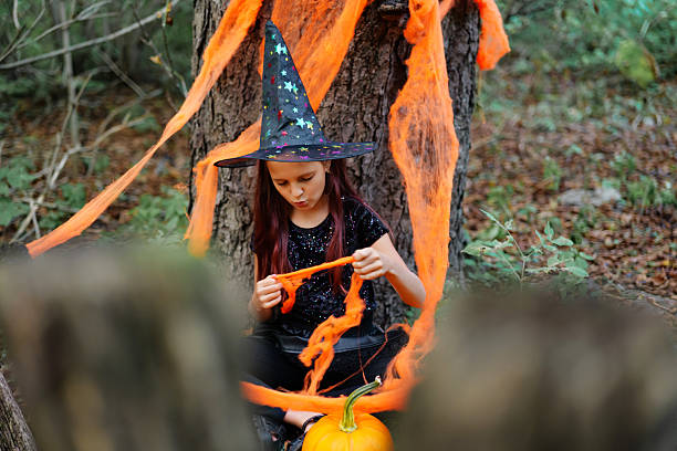 istock Young witch in a forest with orange decorations and pumpkin during Halloween festivities 2235859278
