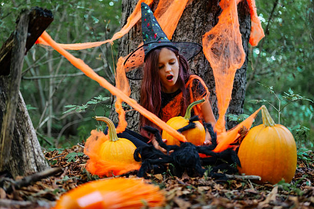 istock Child dressed as a witch plays with pumpkins in a forest during Halloween festivities in autumn 2235859282