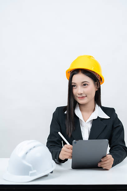 istock A studio shot on a white background shows an Asian female engineer at her desk with a tablet and greenprint, preparing to share innovative designs with the industry through social media platforms. 2235859757