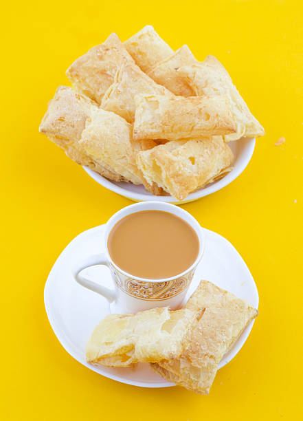 Indian Tea Time Breakfast Khari Also Know as Kharee, Khari Biscuit or Salty Puff Pastry Snacks, Served with Indian Hot Masala Chai or Hot Tea on Yellow Background
