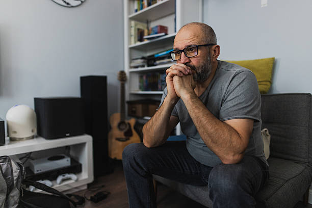 Man Sitting on Floor Holding Head in Thoughtful Moment. He has problems in his life
