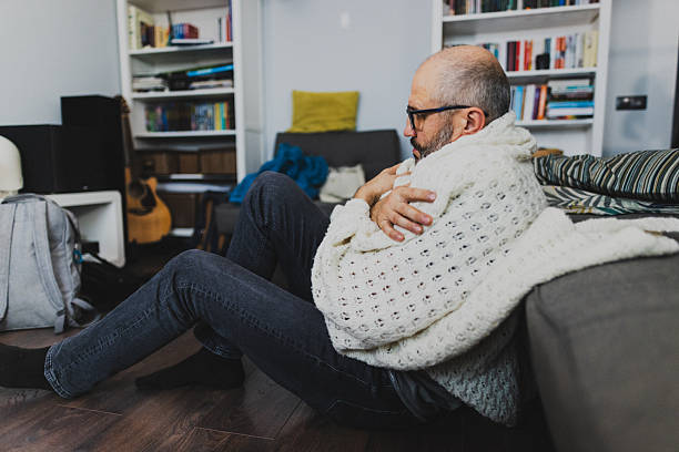 istock Man Sitting on Floor Holding Arms to Keep Warm. He feels Cold in aCozy Home Setting 2235861463